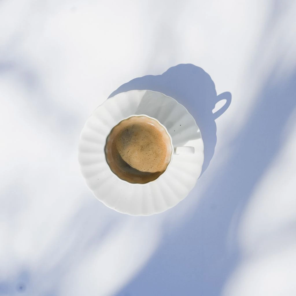 A single demitasse of espresso on a ceramic saucer, fresh crema.