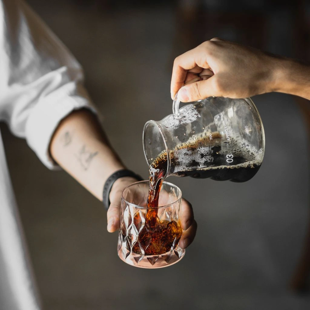 A glass server decanting a reserve-lot single-origin coffee.